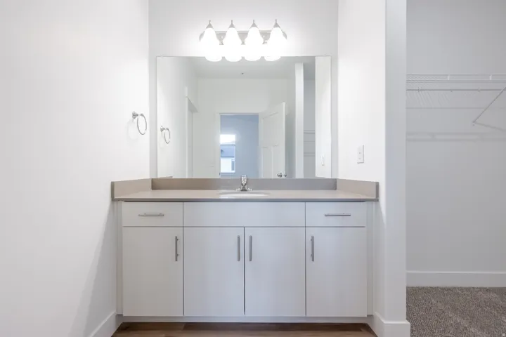 White vanity with silver-tone hardware, rectangular undermount sink, and light-toned countertop