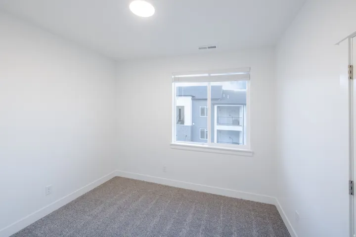 Neutral paint palette with recessed lighting, large window, and gray carpet