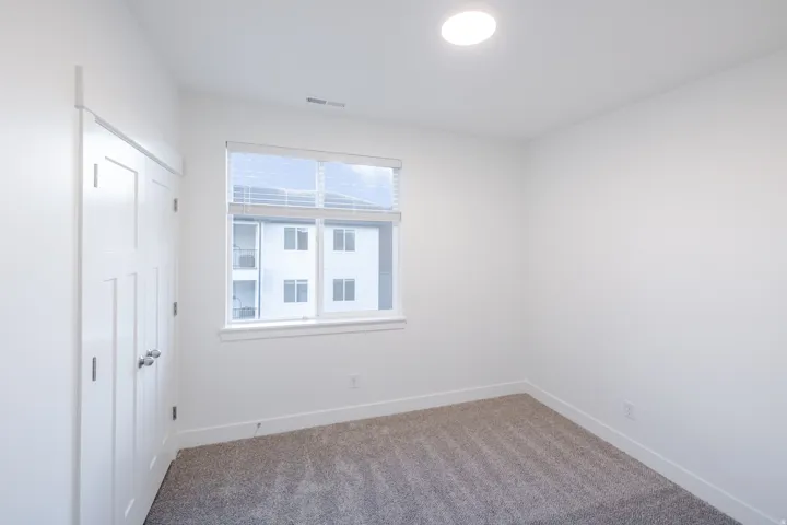 White interior walls, gray carpet flooring, white trim, recessed lighting, and a double-panel door