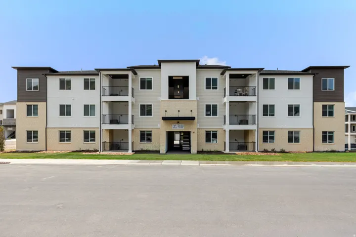 Multi-story building featuring a blend of light-colored siding, brick veneer, and dark accent siding