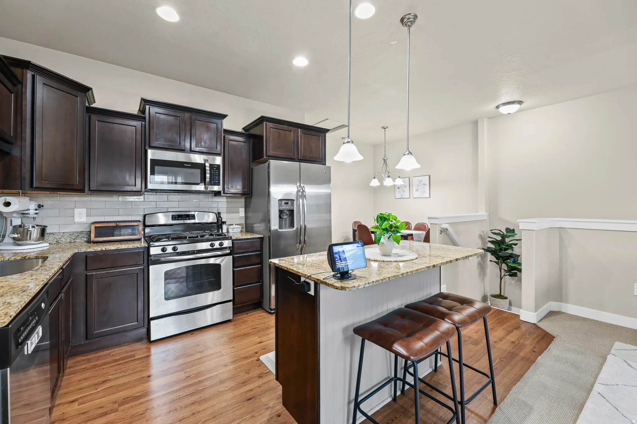 Kitchen featuring a kitchen island, light stone countertops, stainless steel appliances, and dark wood finish cabinets