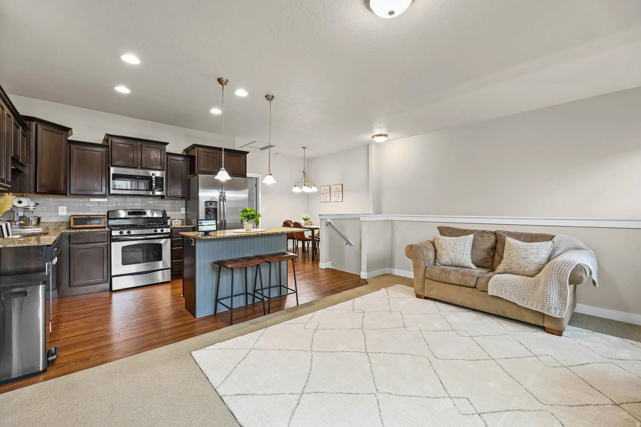 Kitchen with a center island, stainless steel appliances, light stone counters, dark wood finish cabinetry, and decorative backsplash