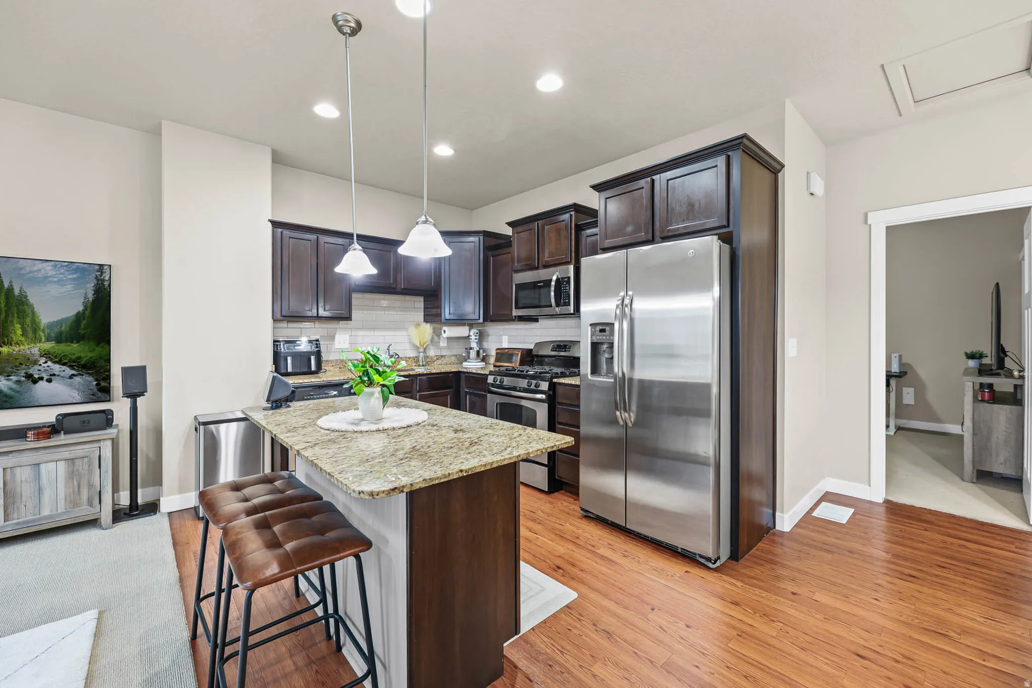 Kitchen with dark wood finish cabinets, stainless steel appliances, light stone countertops, and a kitchen island