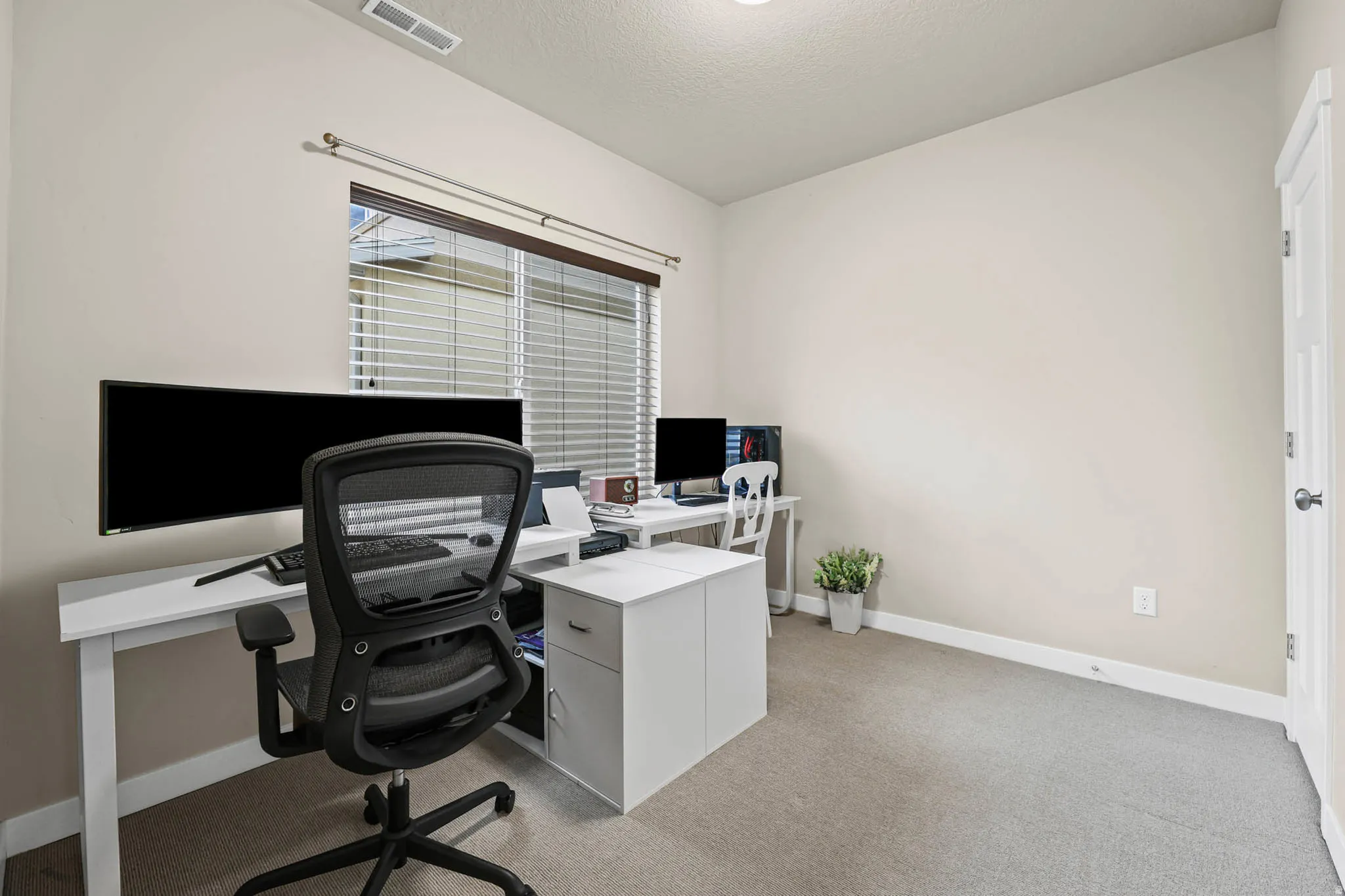 Office area featuring light carpet and a textured ceiling