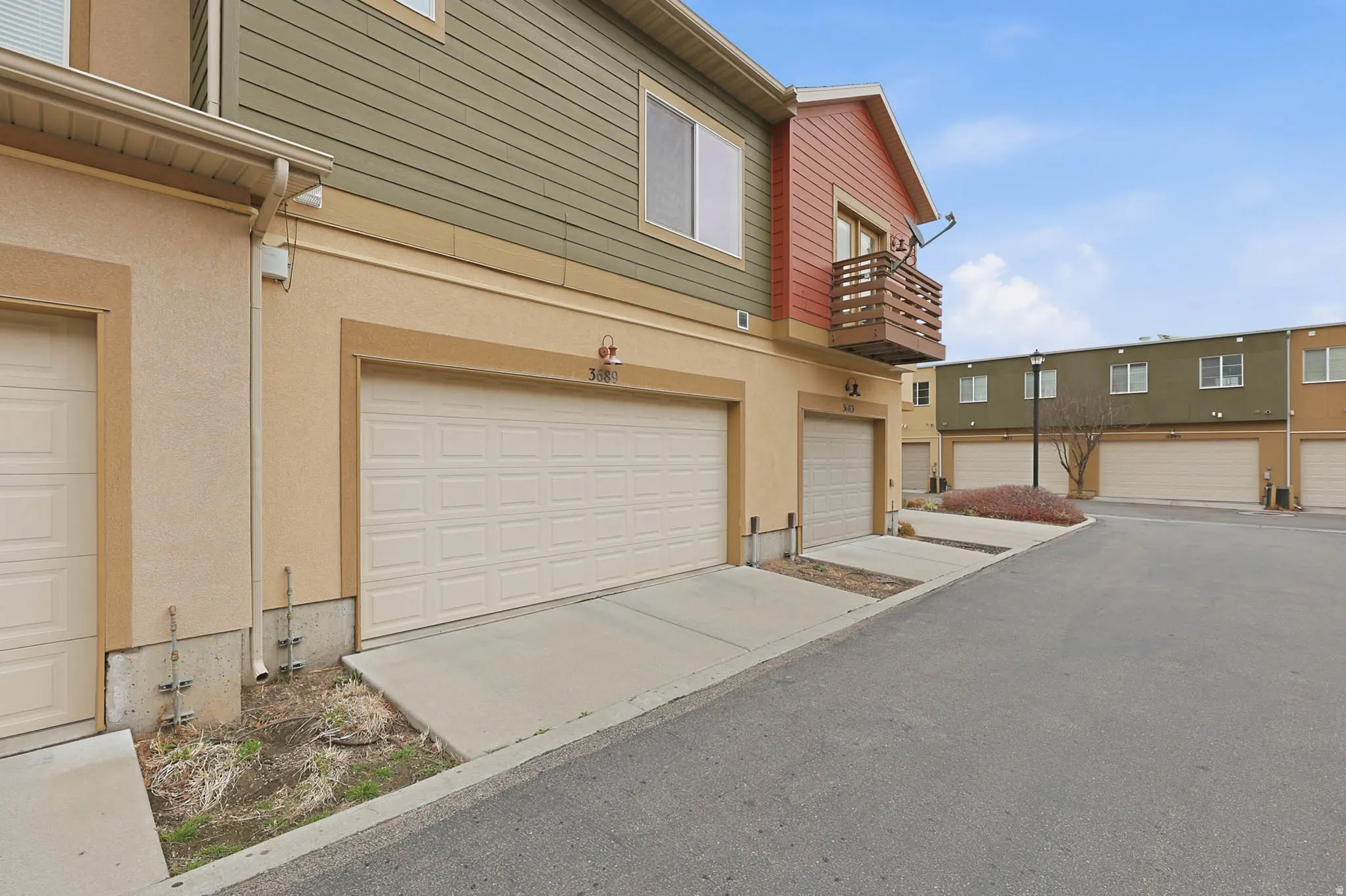 View of side of home with an attached garage, a balcony, stucco siding, and concrete driveway