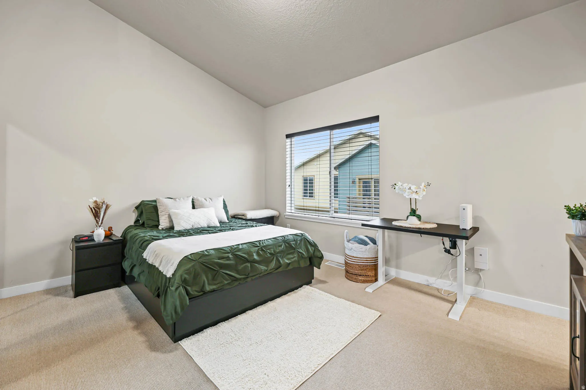 Bedroom featuring light carpet and vaulted ceiling