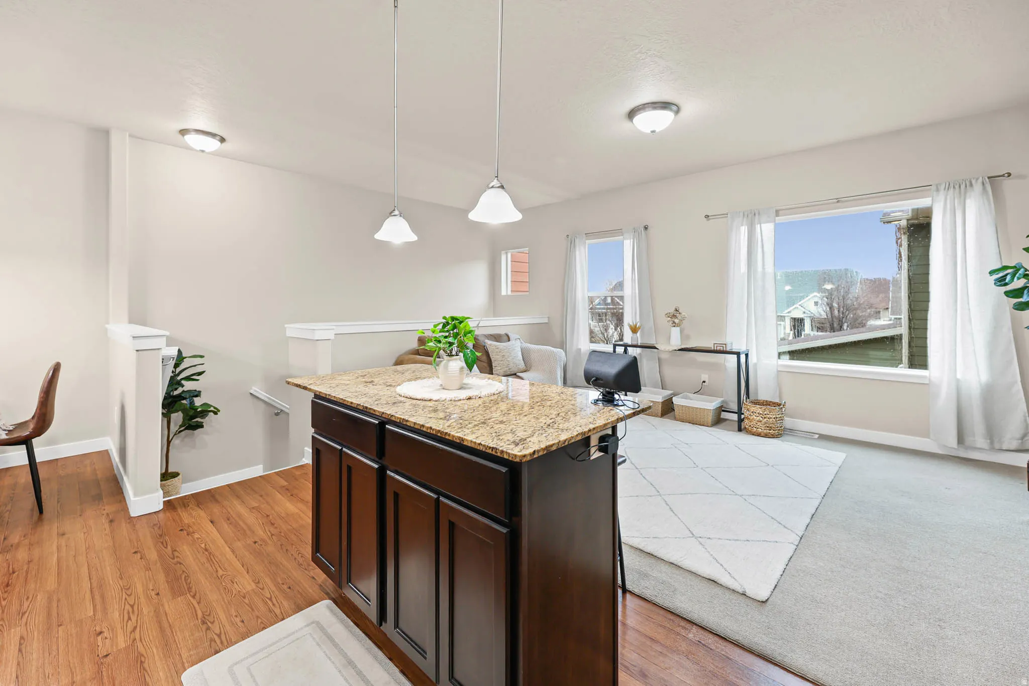 Kitchen with dark wood finish cabinets, a center island, light stone counters, pendant lighting, and light wood-style flooring