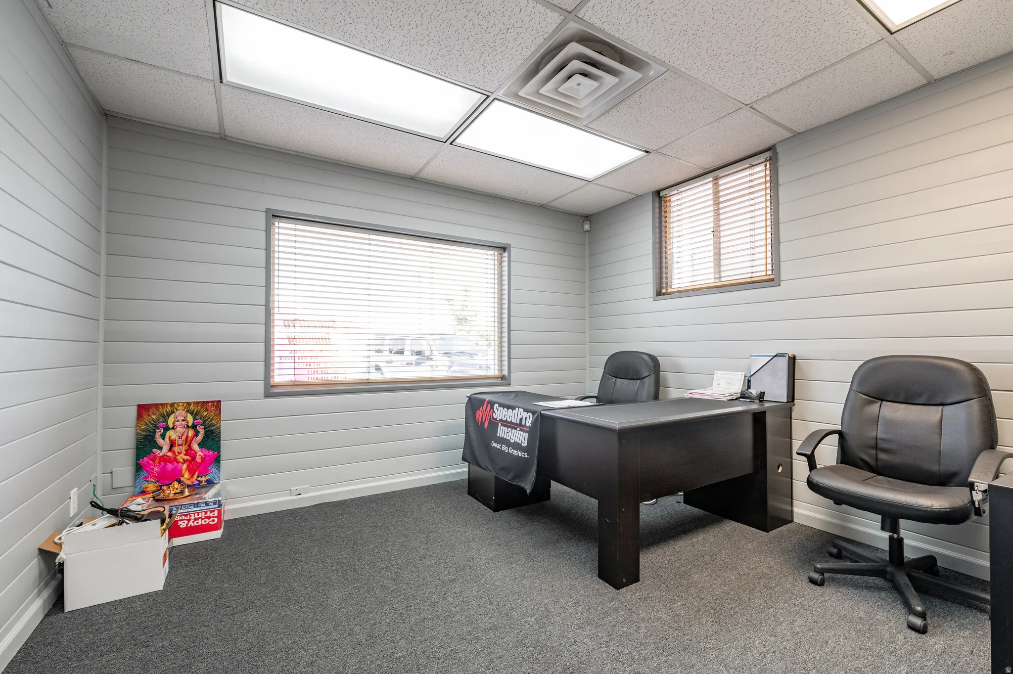 Home office featuring a drop ceiling and wood walls