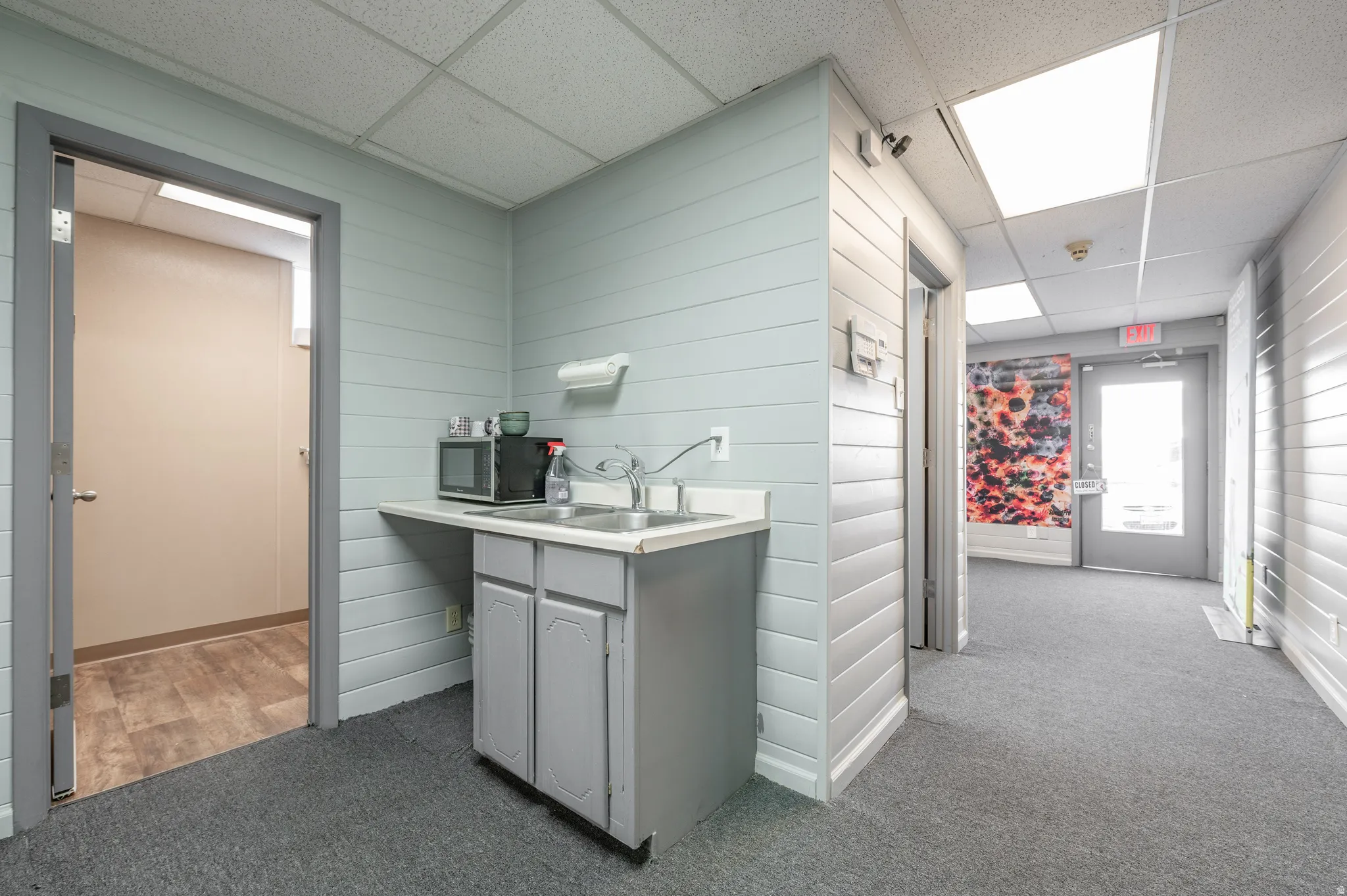 Bar featuring a drop ceiling, light countertops, stainless steel microwave, and gray cabinets