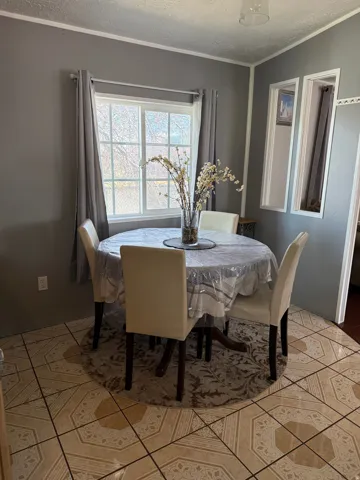 Dining space with a textured ceiling, ornamental molding, and light tile patterned flooring