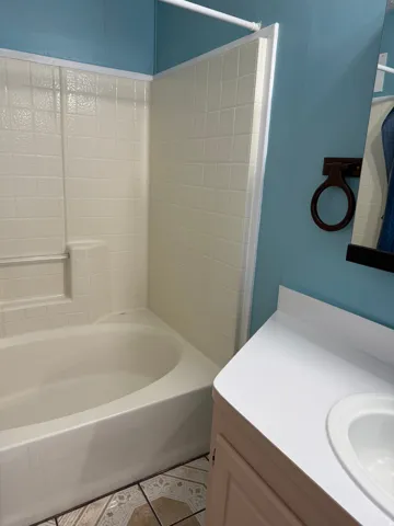 Bathroom featuring vanity, bathing tub / shower combination, and light tile patterned flooring