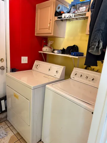 Laundry room with washing machine and clothes dryer, cabinet space, and light tile patterned floors