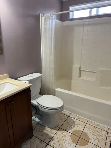 Full bath with vanity, shower / tub combo, and light tile patterned floors