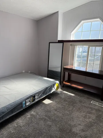 Bedroom featuring dark colored carpet and a textured ceiling