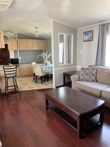 Living room with cooling unit, light wood-type flooring, ornamental molding, and plenty of natural light