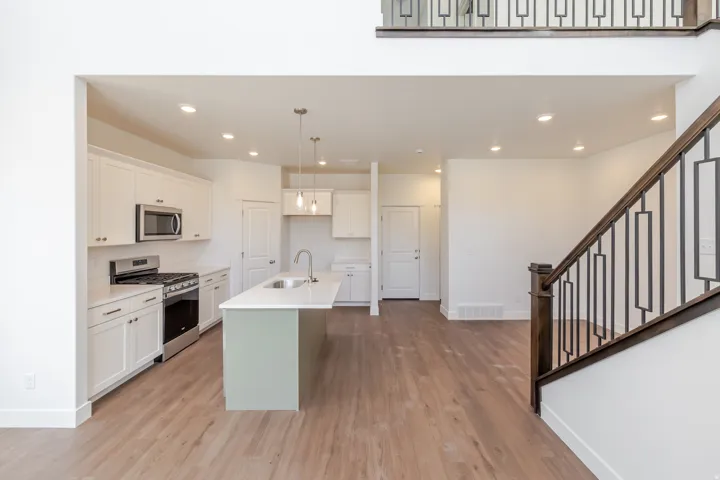Modern kitchen featuring white shaker cabinetry, stainless steel appliances, and a light green island with a stainless steel sink