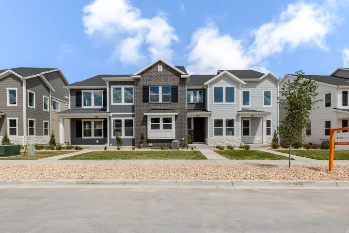 Contemporary townhome facade featuring a dark gray brick and siding exterior, white trim, and black window shutters