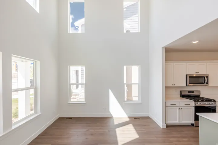 Expansive living area featuring vaulted ceilings, wood-finish flooring, and multiple windows