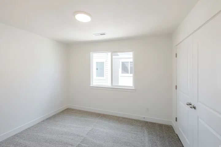 Carpeted room with a double-paned window, white trim, and a flush-mount ceiling light