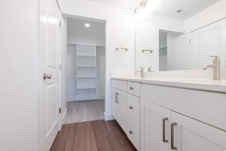 Double vanity with white cabinetry, light-toned countertops, and brushed nickel hardware
