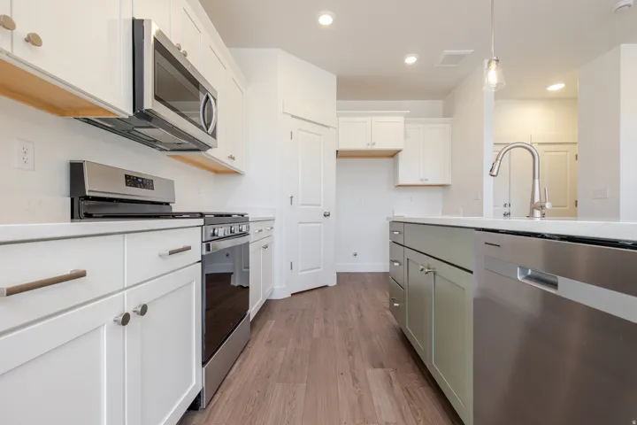 Modern kitchen featuring white cabinetry, stainless steel appliances, a center island with contrasting cabinetry, wood-finish flooring, and recessed lighting