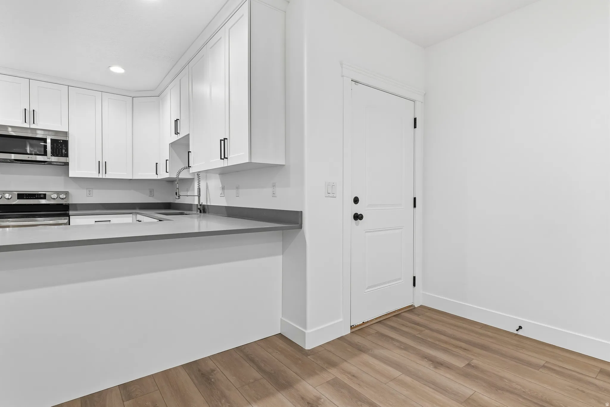 Kitchen featuring stainless steel appliances, white cabinetry, light wood-style floors, and recessed lighting