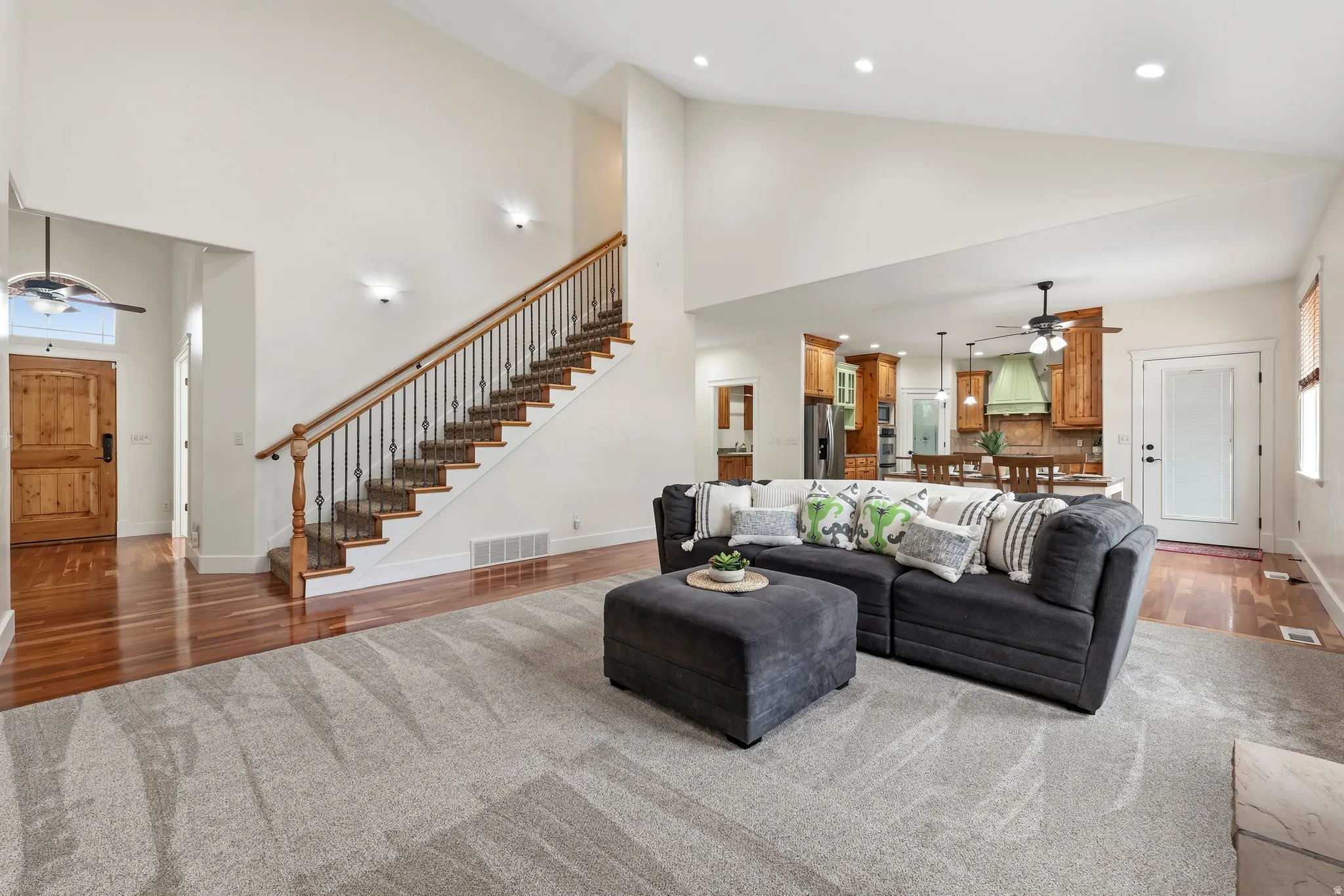 Living room with a ceiling fan, recessed lighting, wood finished floors, healthy amount of natural light, and lofted ceiling