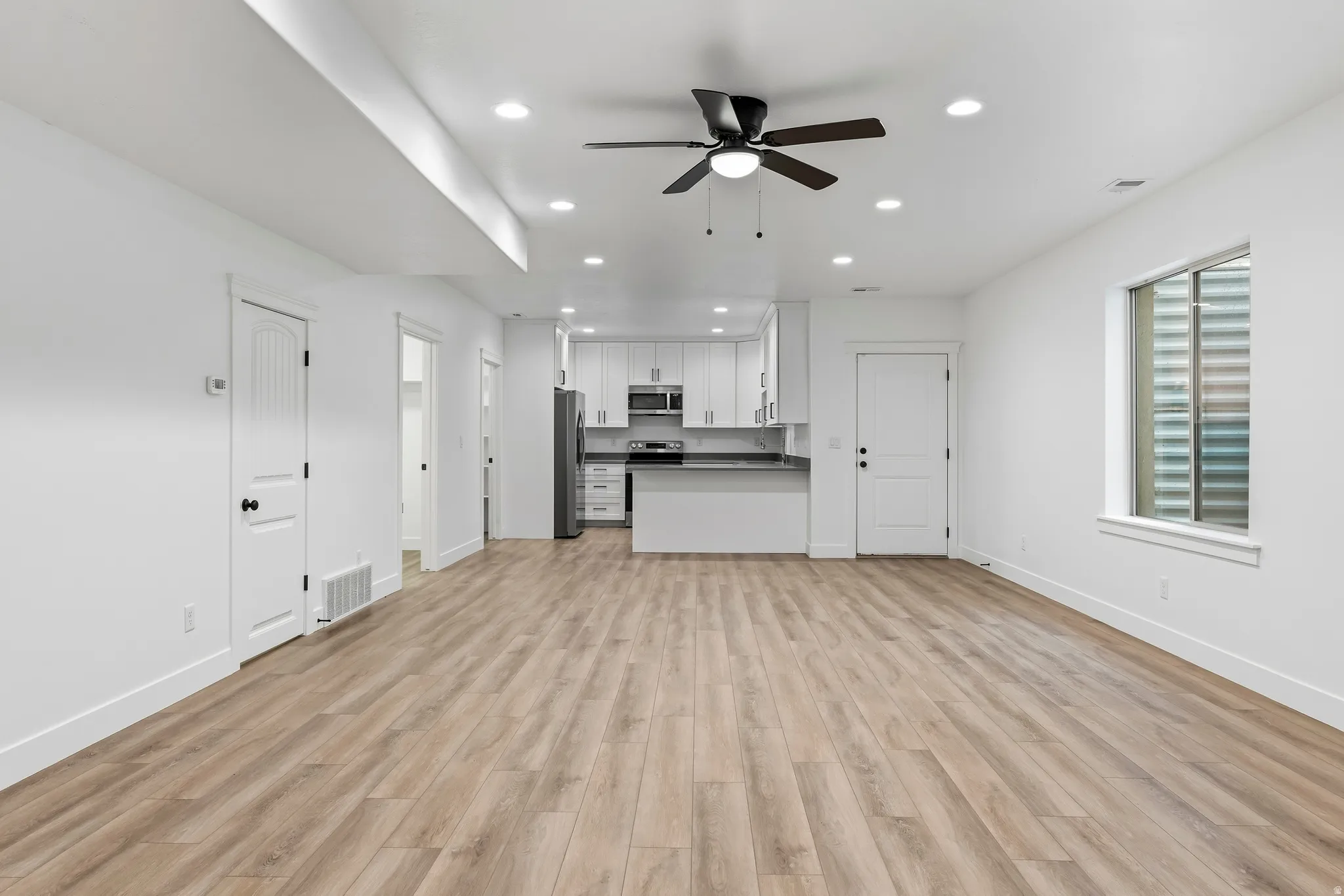 Unfurnished living room with a ceiling fan, recessed lighting, and light wood finished floors