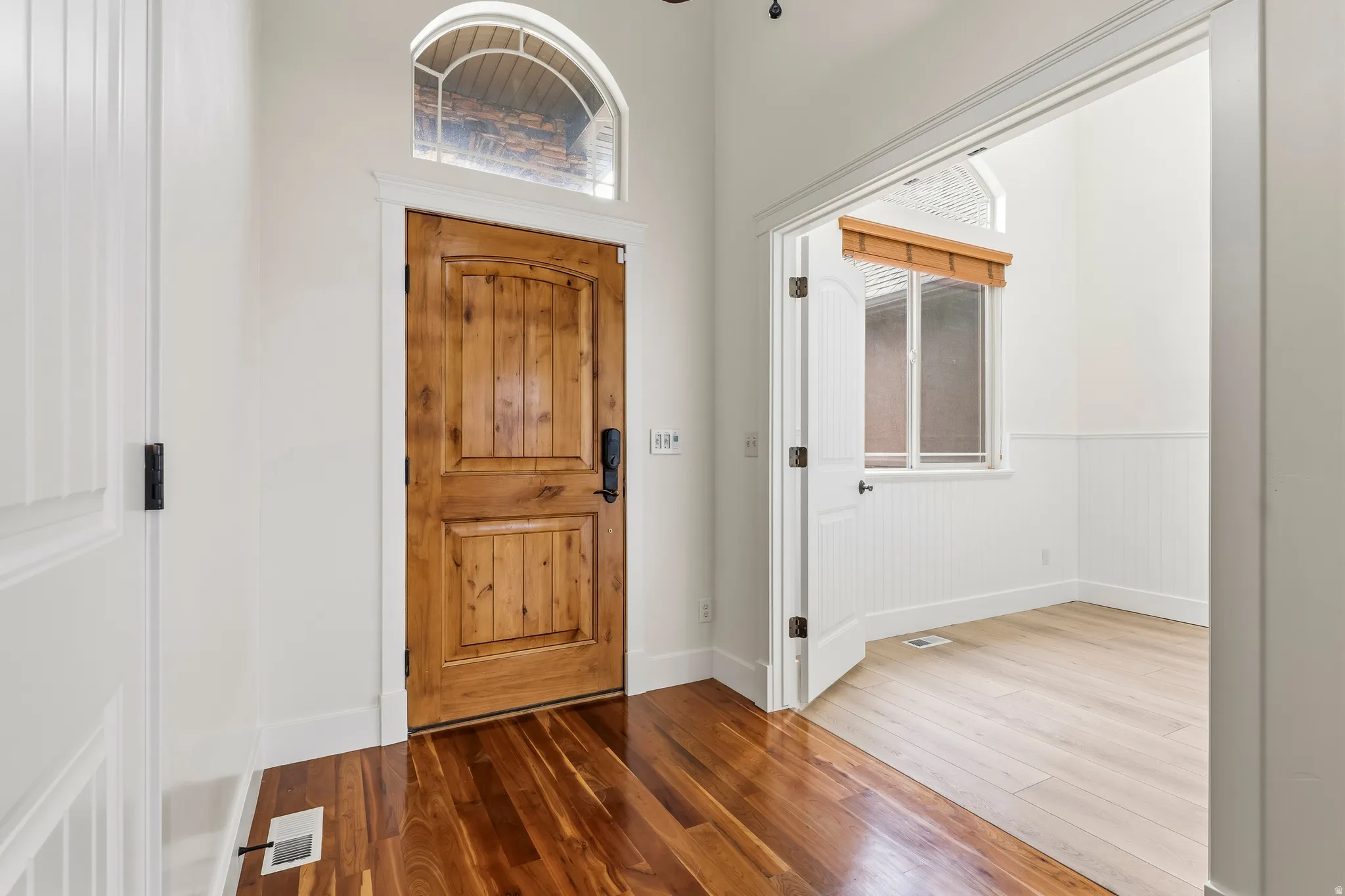 Foyer with wood finished floors and a wainscoted wall