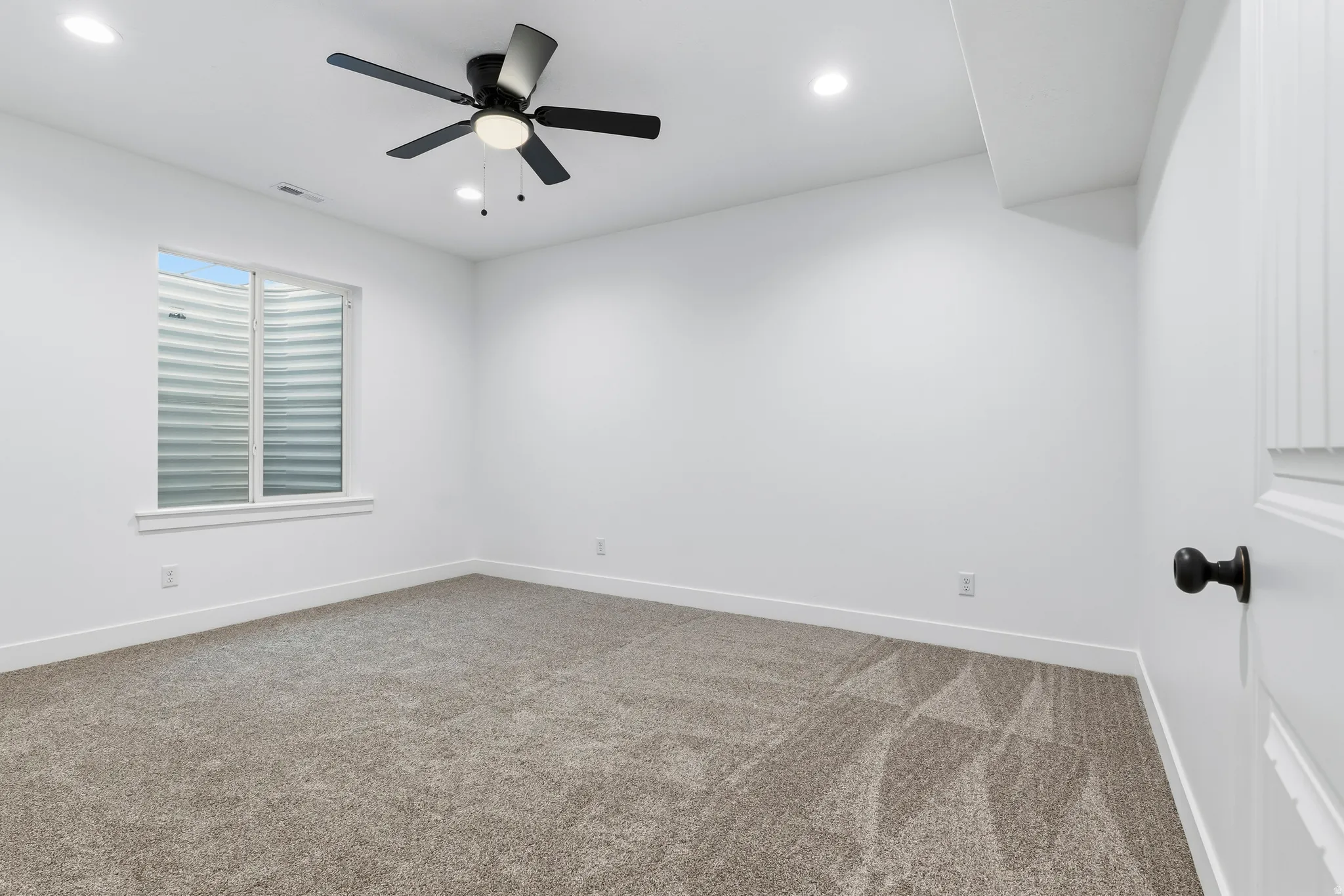 Carpeted empty room with ceiling fan and recessed lighting