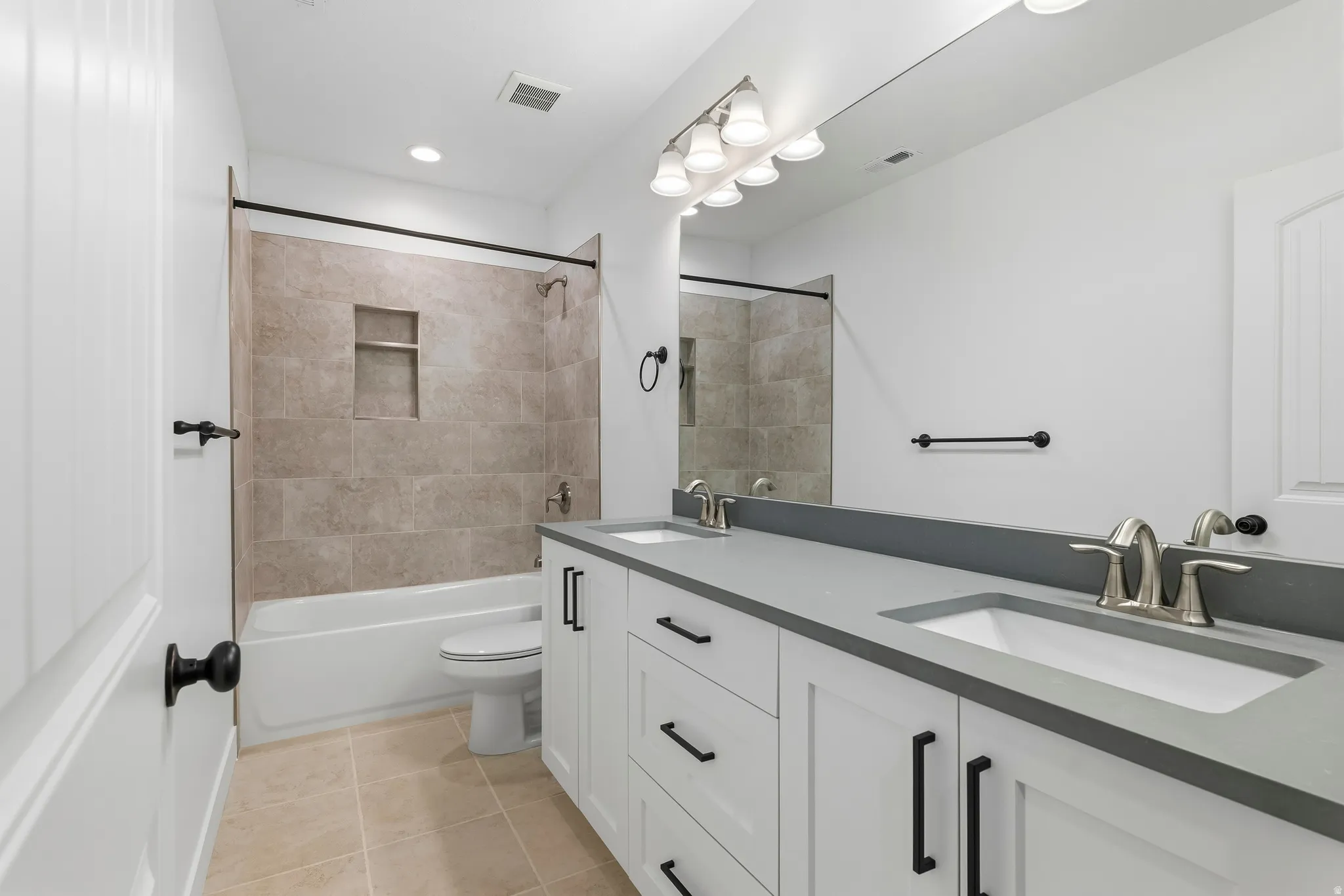 Full bath featuring double vanity, light tile patterned floors, and shower / tub combination
