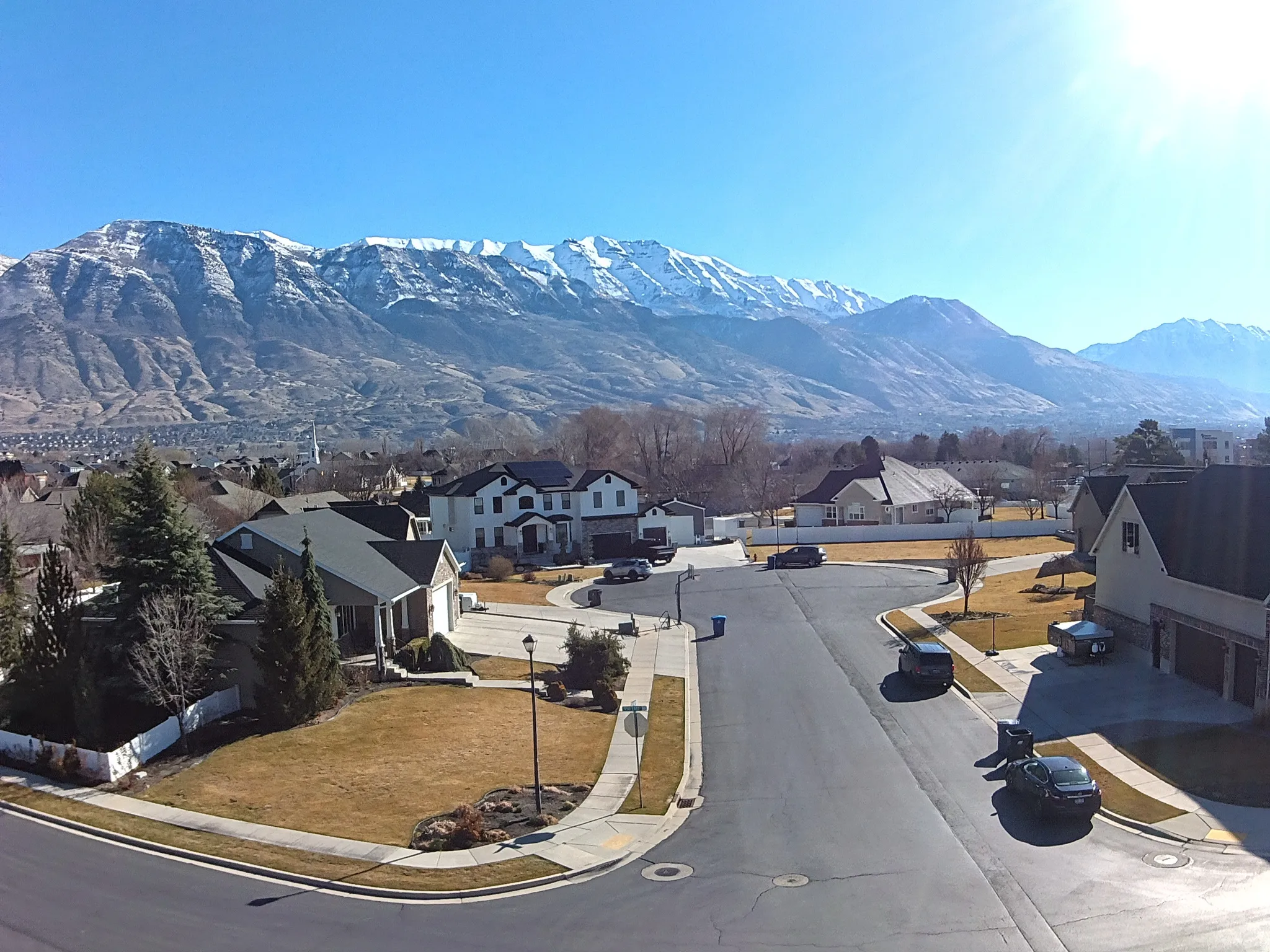 View of asphalt street with sidewalks, a residential view, curbs, and a mountain view