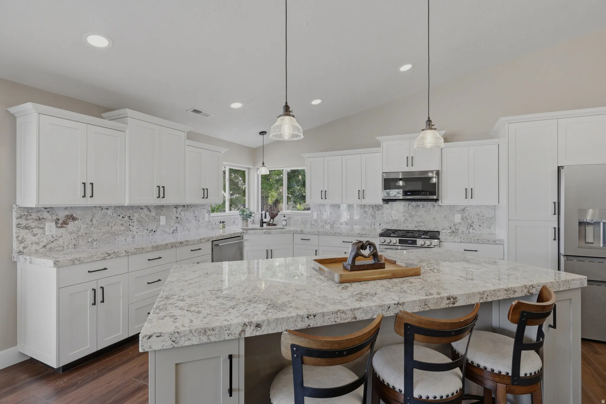 Kitchen with a kitchen breakfast bar, a center island, dark wood finished floors, decorative light fixtures, and vaulted ceiling