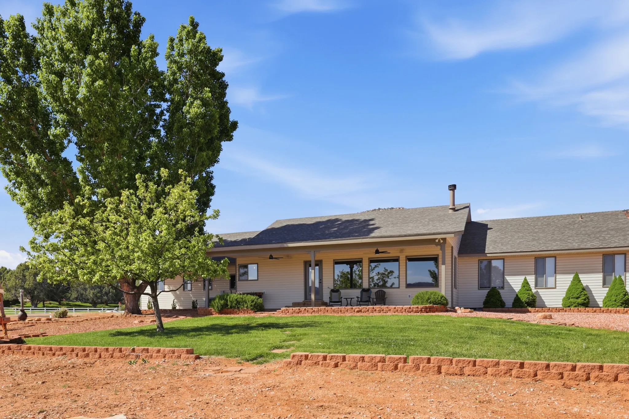 View of front of house featuring a front yard, ceiling fan, a shingled roof, and a patio