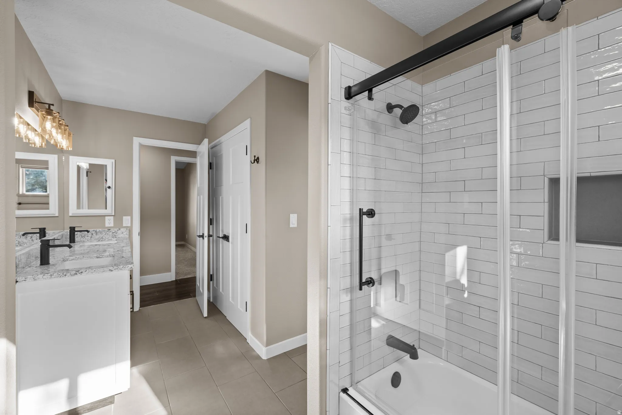 Jack and Jill bathroom featuring double vanity, light tile patterned flooring, and enclosed tub / shower combo