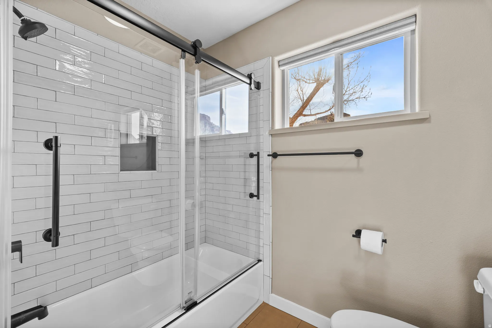 Jack and Jill bathroom featuring toilet and combined bath / shower with glass door