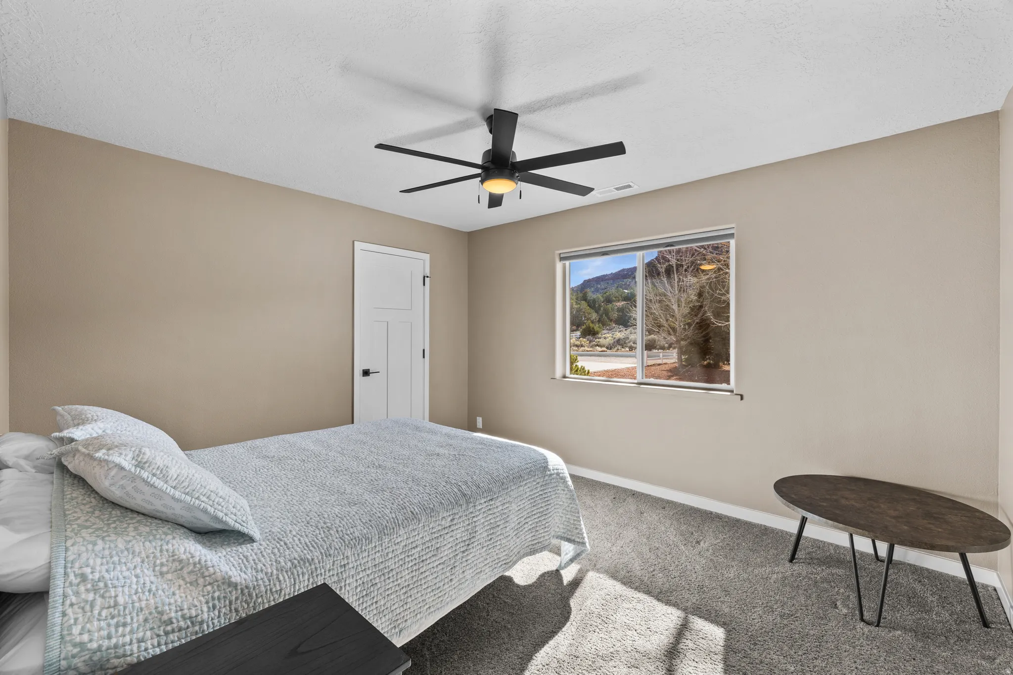 Carpeted bedroom with ceiling fan and a textured ceiling