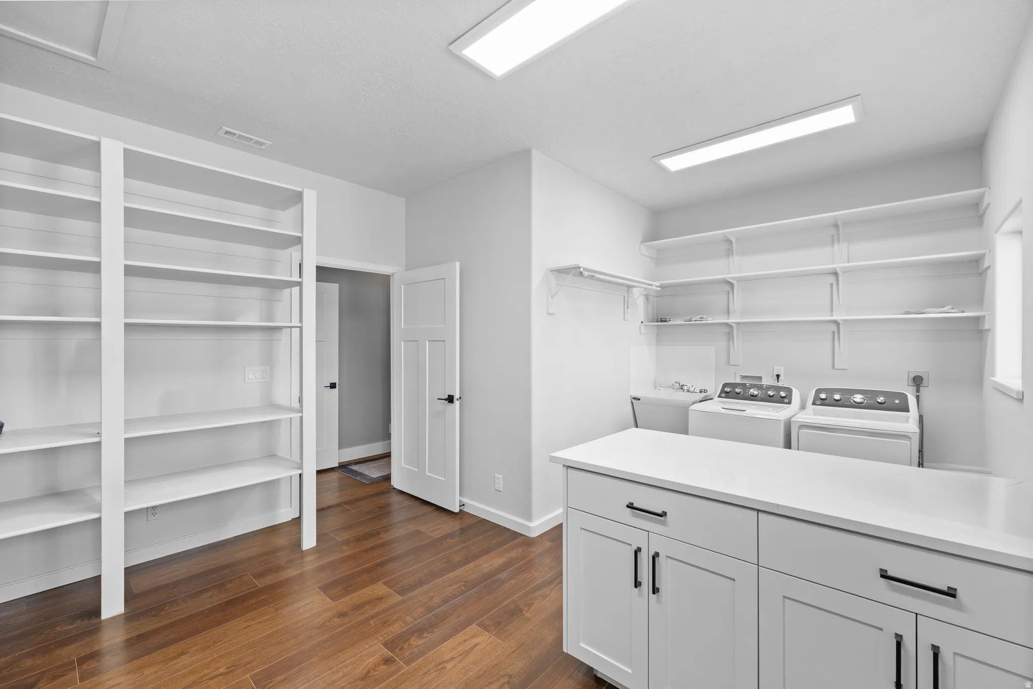 Laundry room featuring dark wood-style flooring, independent washer and dryer, and ample storage space