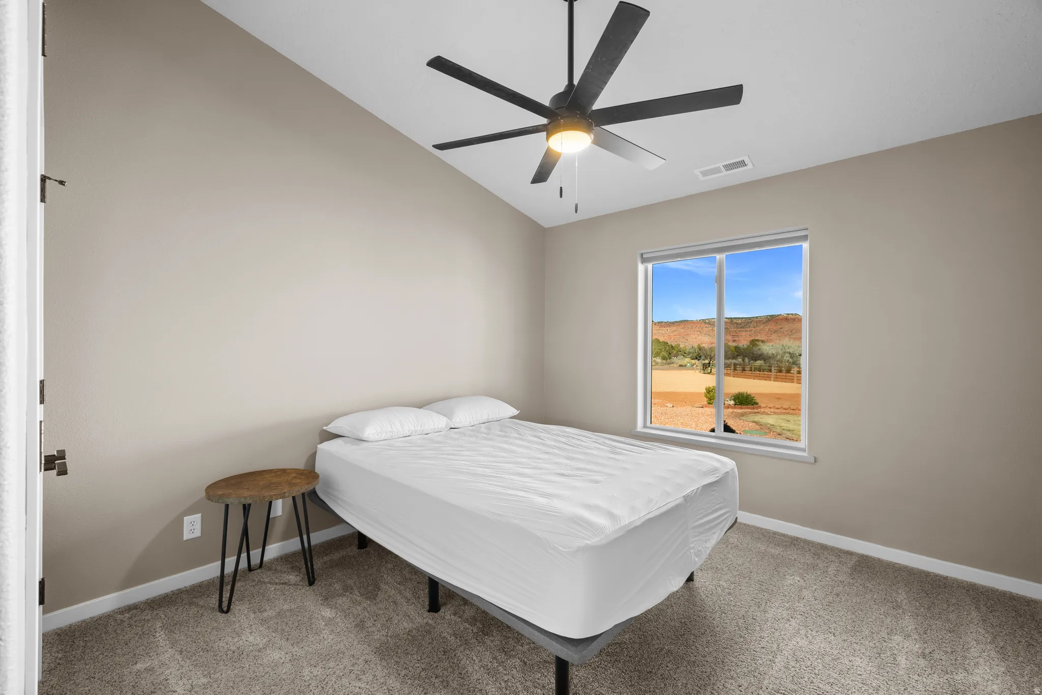 Bedroom with vaulted ceiling, a ceiling fan, a mountain view, and light carpet