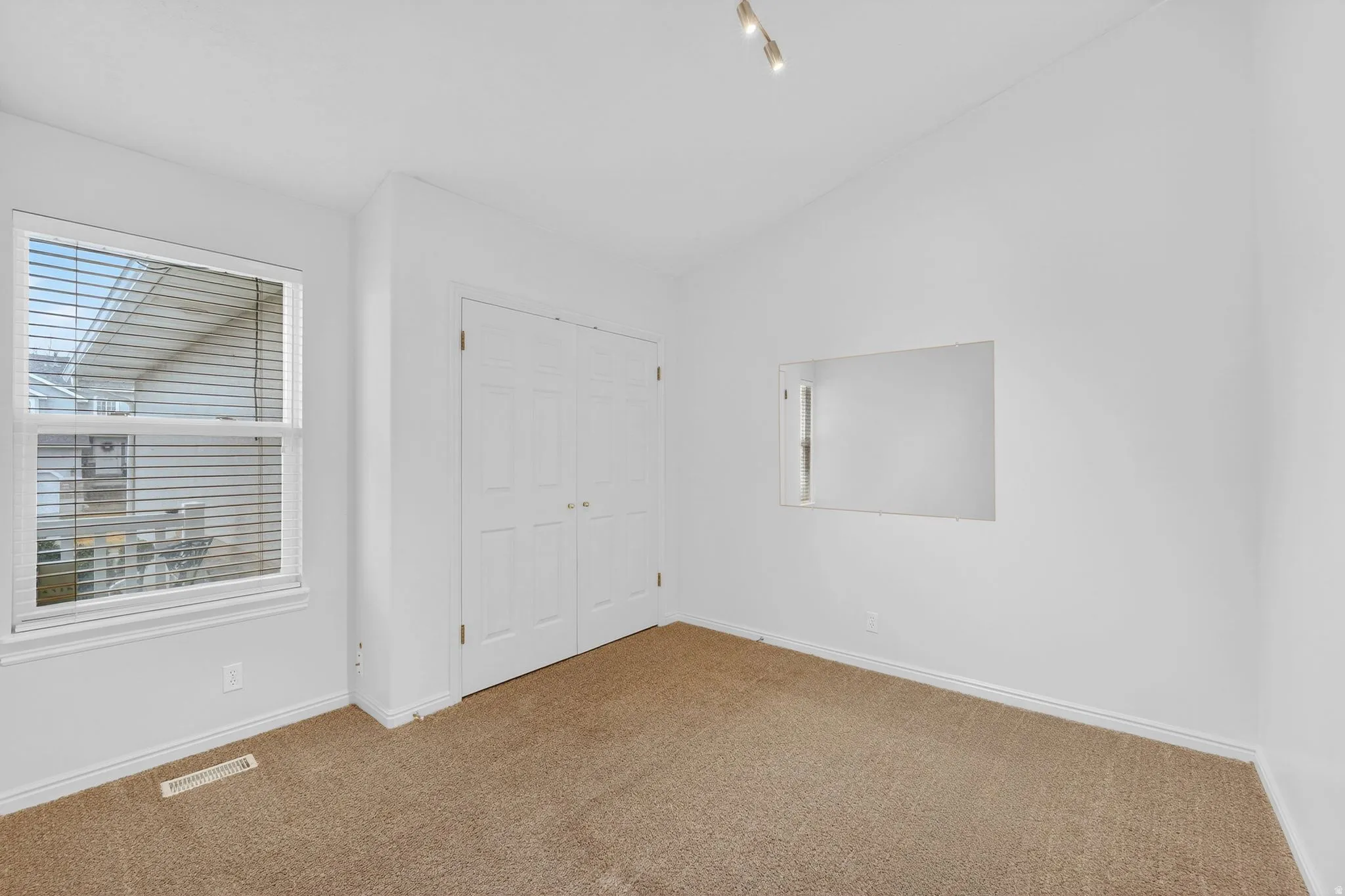 Unfurnished bedroom with carpet floors, lofted ceiling, a closet, and multiple windows