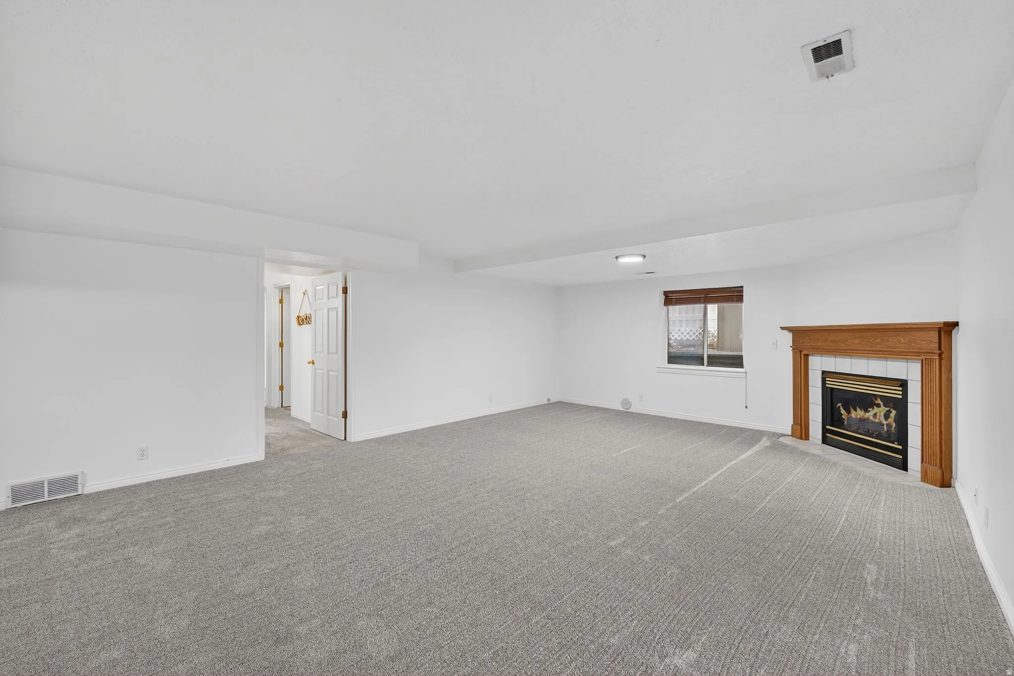 Unfurnished living room with a tiled fireplace and carpet