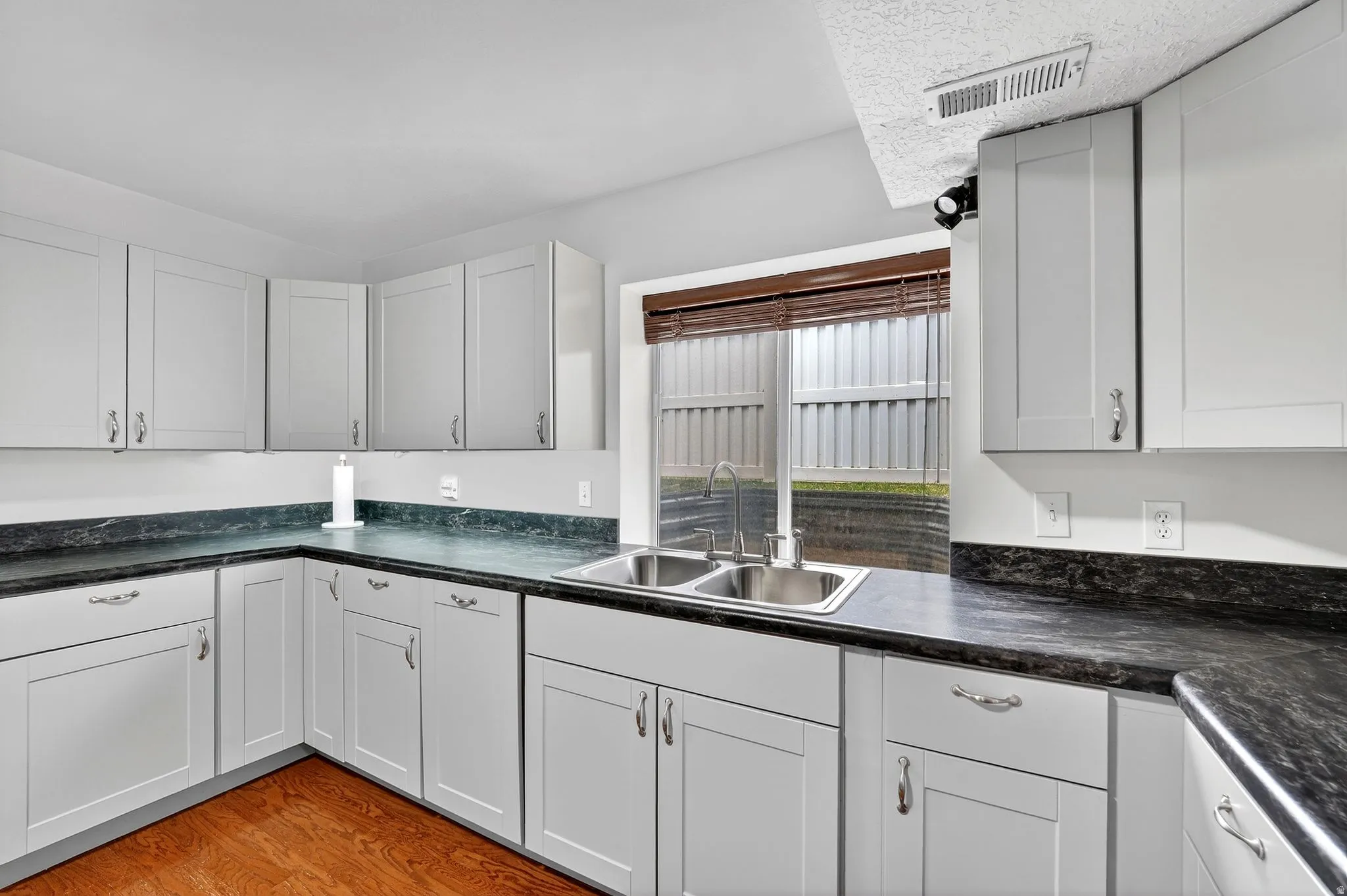 Kitchen featuring dark countertops, light wood finished floors, and white cabinetry