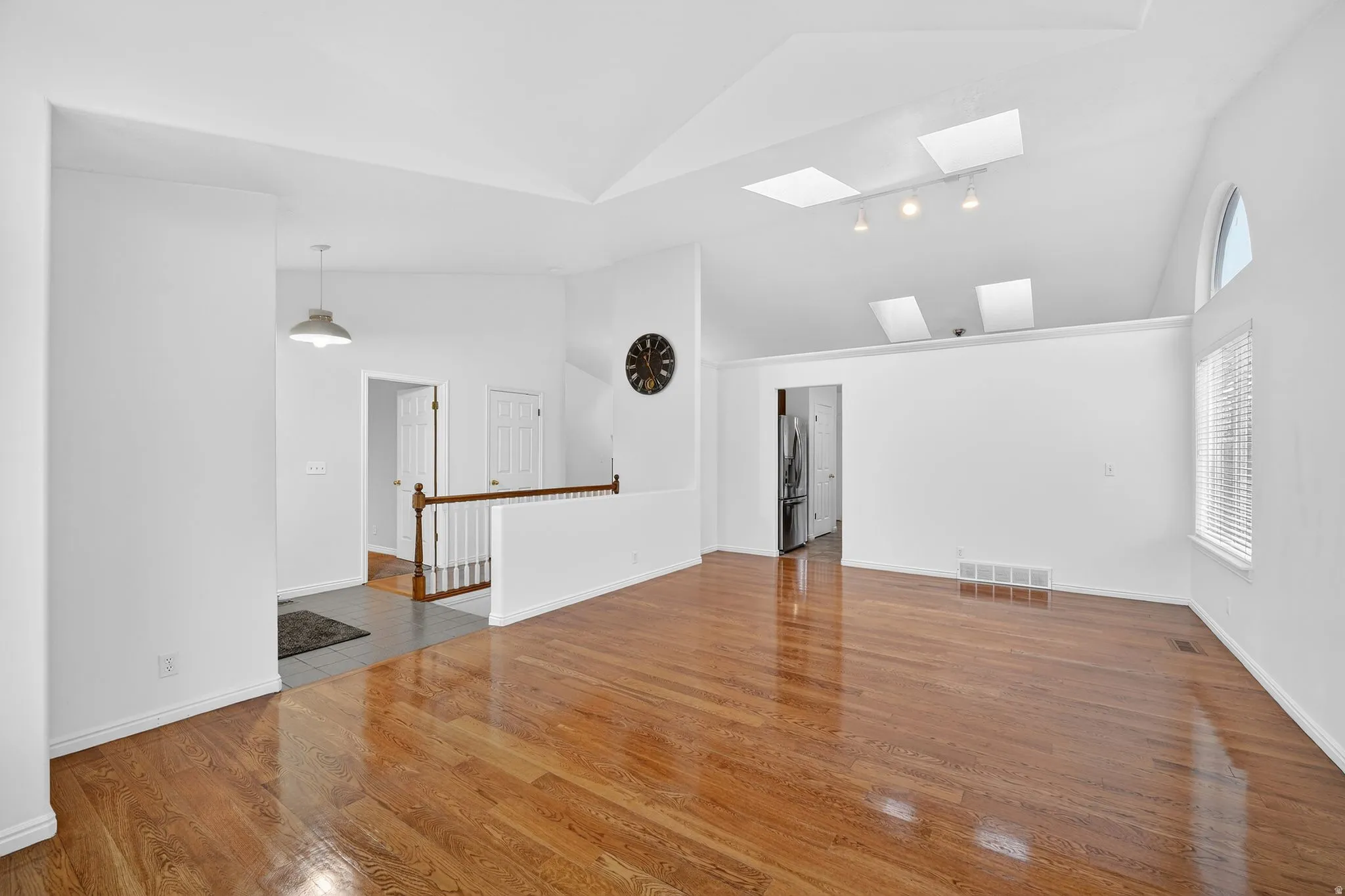 Empty room with light wood finished floors, vaulted ceiling, and a skylight