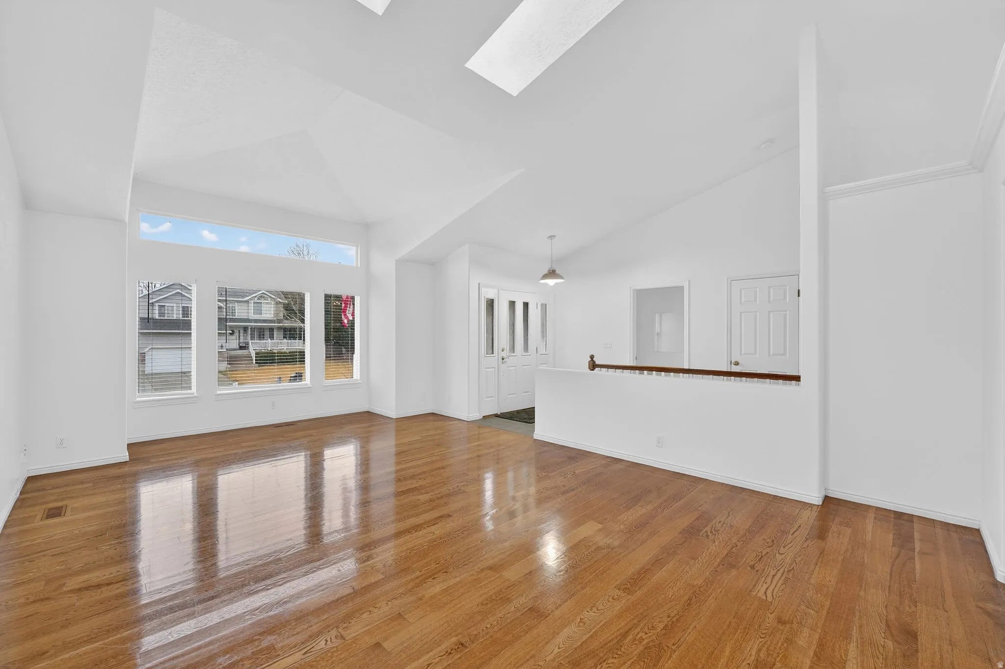Unfurnished living room featuring a skylight, light wood-type flooring, and lofted ceiling