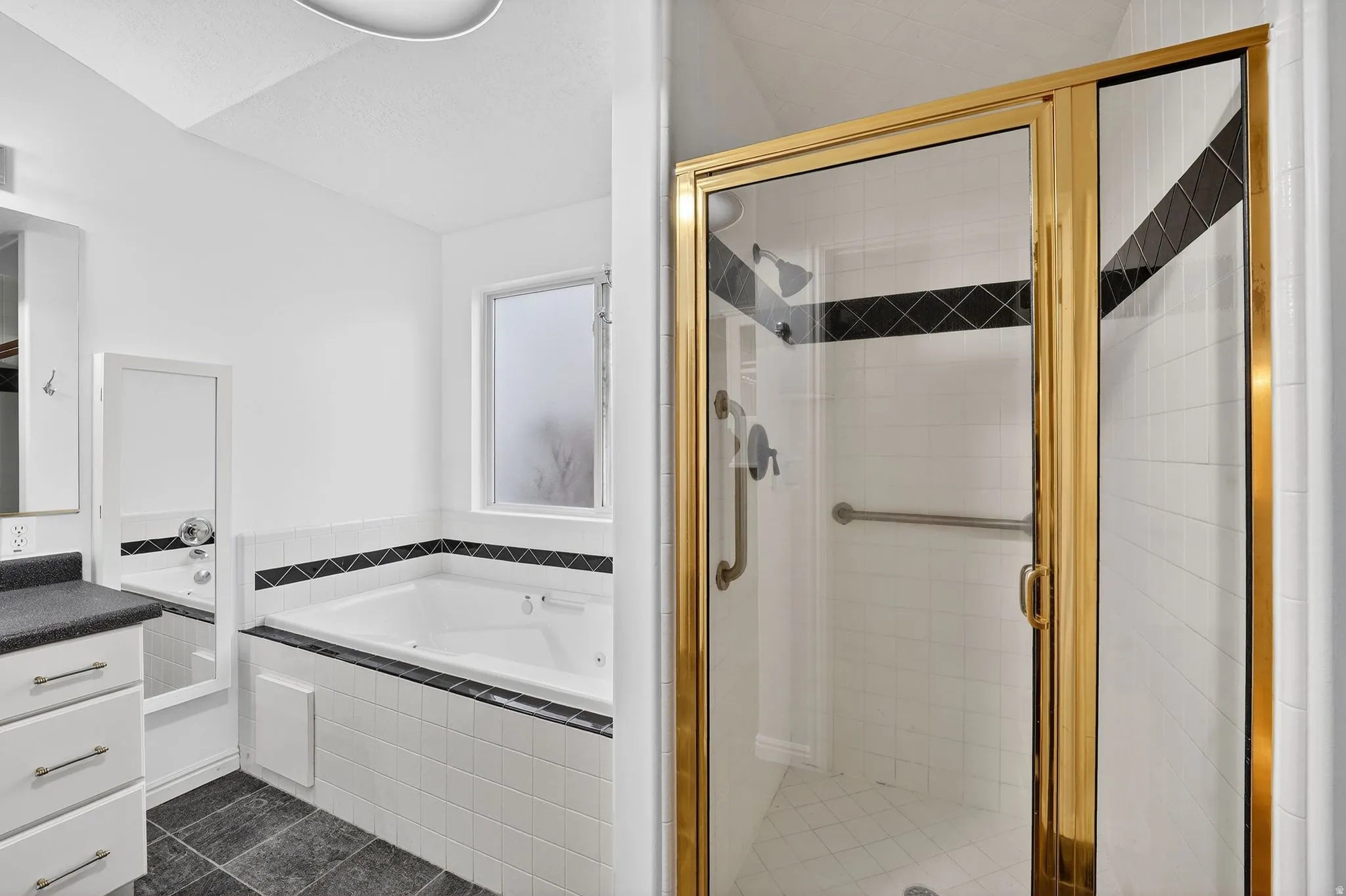 Full bathroom with vanity, a bath, a shower stall, and dark tile patterned floors