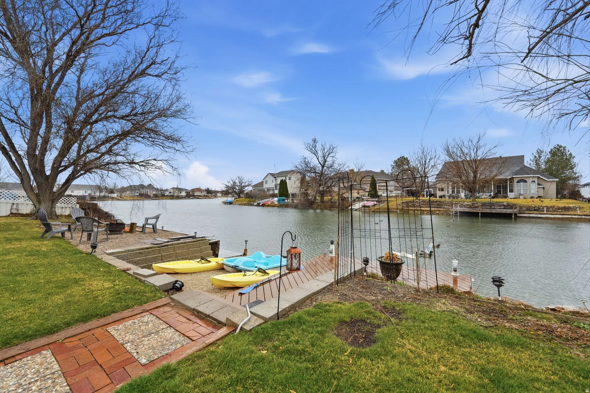Dock with a water view, a residential view, a lawn, and a patio area