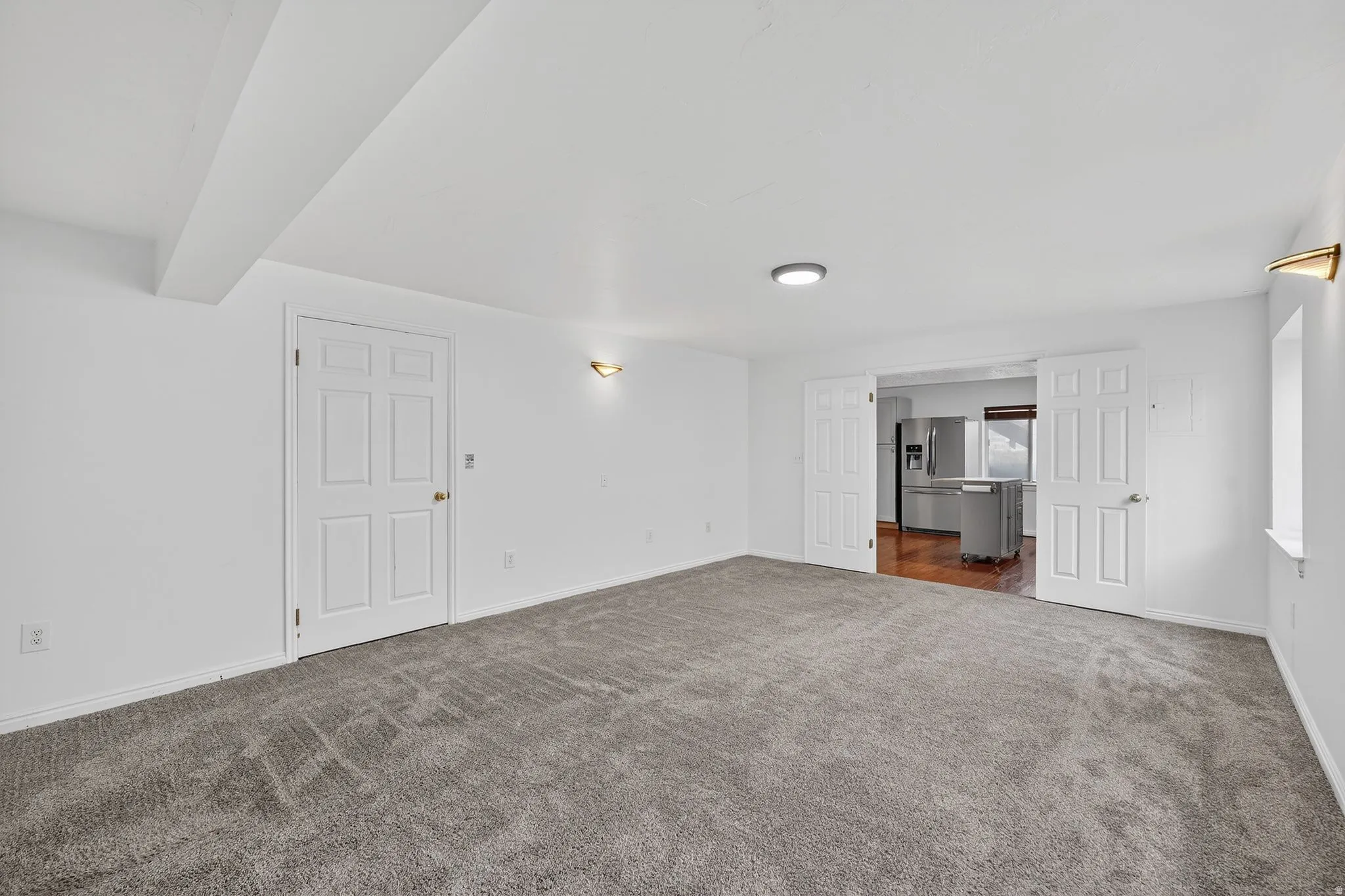 Unfurnished living room featuring dark carpet and beam ceiling