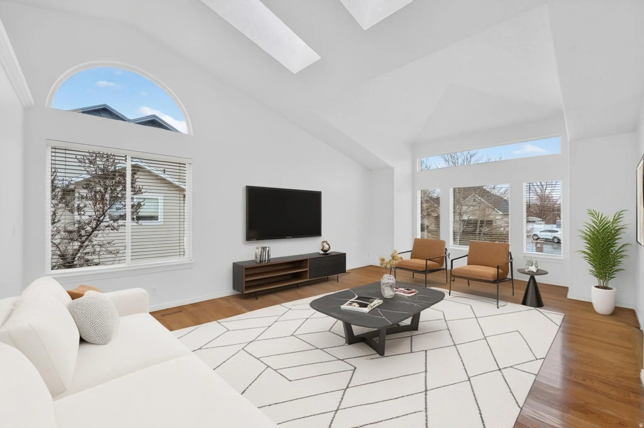 Living room with a skylight, vaulted ceiling, light wood-style flooring, and healthy amount of natural light