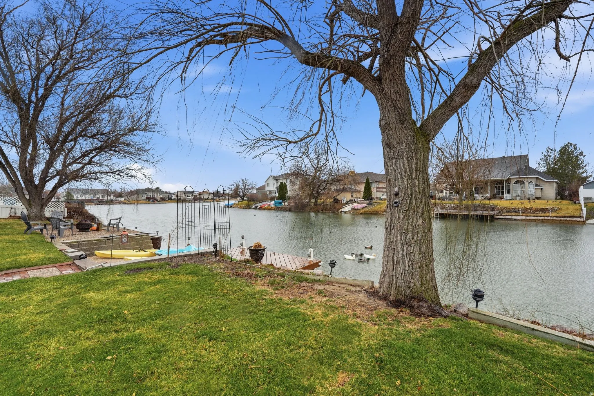 View of green lawn with a boat dock, a residential view, and a water view