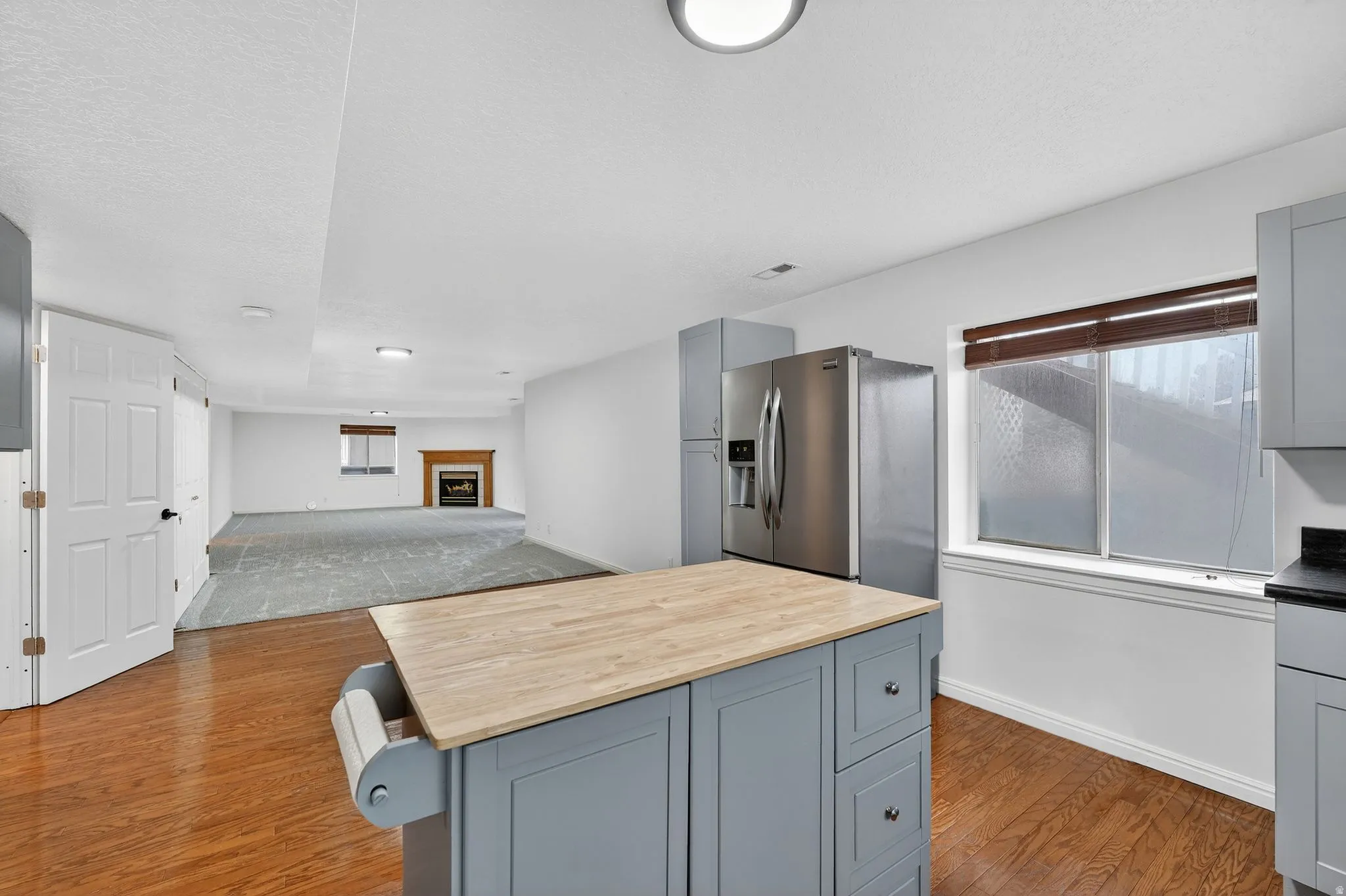 Kitchen with gray cabinets, open floor plan, wooden counters, a breakfast bar, and a textured ceiling